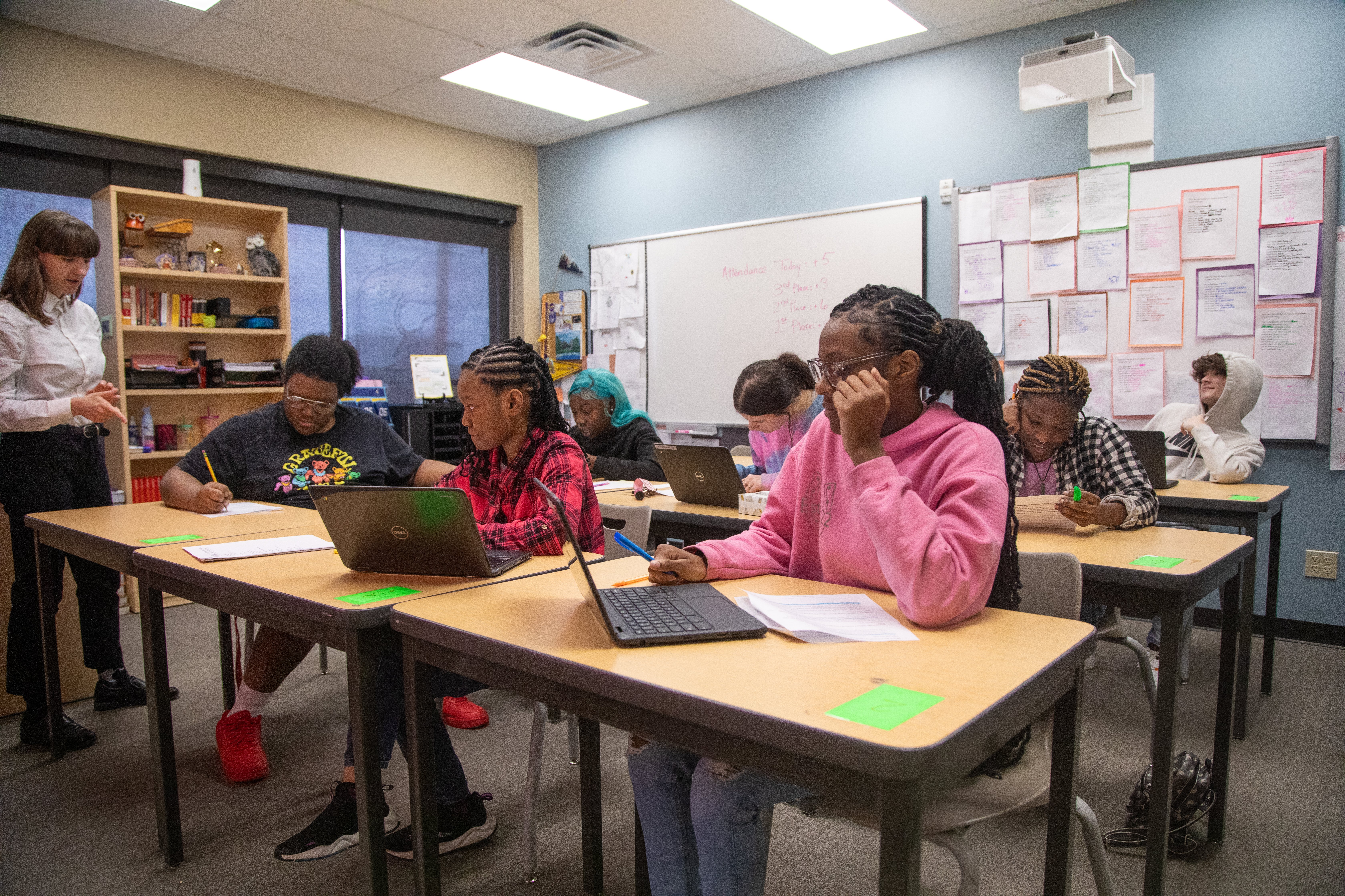 A small group of students learning in a classroom with laptops.