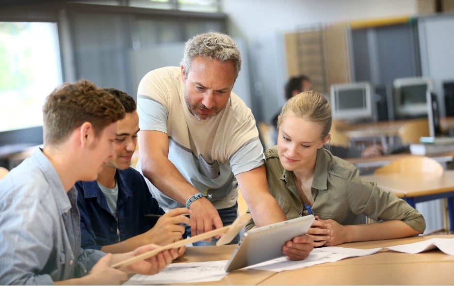 Students learning with a teacher in a classroom.