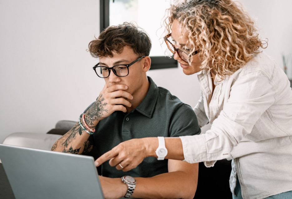 A teacher helping a student on a laptop.